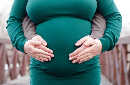 Close-up of parents having their hands resting on mom's pregnant belly