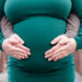 Close-up of parents having their hands resting on mom's pregnant belly