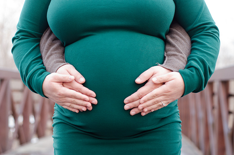 Close-up of parents having their hands resting on mom's pregnant belly