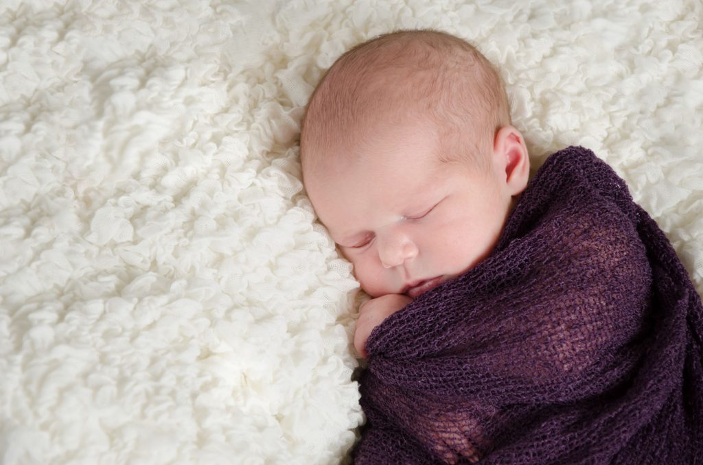 Newborn baby posed in a wrapped position during a studio newborn session in the Twin Cities